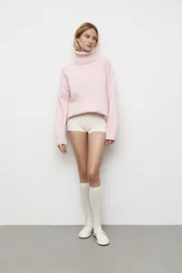 Vue détaillée du pull rose douillet à col roulé, manches longues et coupe ample et confortable.