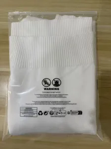 Detailed view of white turtleneck knitted sweater, neatly folded in clear packaging bag.