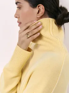 Close-up detail of soft yellow turtleneck knit sweater, cozy autumn and winter apparel texture.