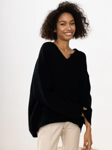 Detailed view of a stylish black V-neck oversized knitted sweater worn by a smiling model.