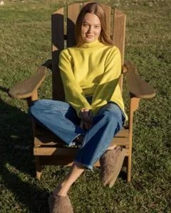 Detailed view of a stylish women's yellow turtleneck sweater, casual loose fit outdoor lifestyle.