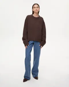 Detailed full-body shot of a casual oversized crewneck knit sweater worn with blue jeans.