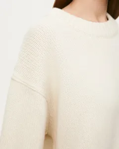 Close-up view of the cream knitted crewneck sweater, showing soft texture and cozy fit.