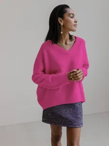 Close-up detail view of a vibrant pink V-neck oversized long sleeve knit sweater worn by model.