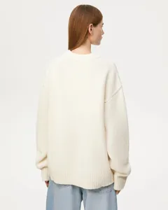 Detail view of a cozy off-white crewneck knitted sweater showing relaxed fit and ribbed hem.