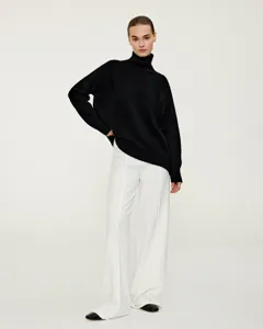 Details of casual black turtleneck sweater and white wide leg trousers on fashion model.