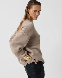 Detailed view of women's cozy knit sweater in beige, featuring a relaxed crew neck and long sleeves.