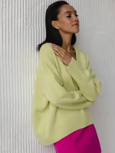 Detail shot of light green loose V-neck knit sweater sleeve and texture closeup.