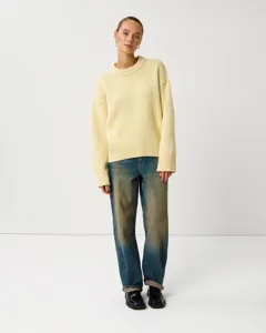 Detailed view of women's light yellow crew neck knit sweater worn by model, cozy texture.
