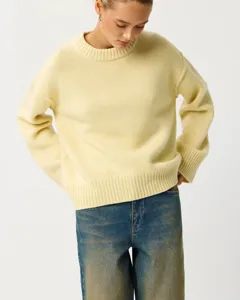 Close-up detail shot of the soft light yellow knit sweater showing ribbed crewneck texture.