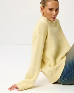 Detailed shot of a stylish light yellow high neck knit sweater featuring cozy long sleeves.