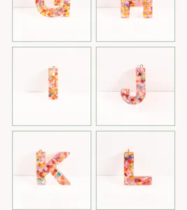 Close-up detail shot of resin letter pendants filled with colorful heart sequins for DIY jewelry.