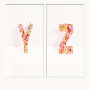 Close-up detail of pink glitter resin letter Y and Z pendant charms for custom DIY accessories.