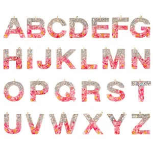 DIY resin letter pendant charms with pink crushed shells and silver glitter for jewelry making.