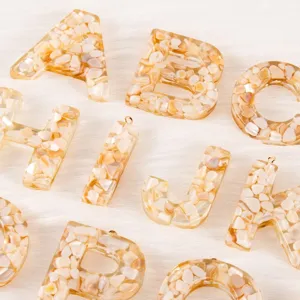 Detail shot of resin alphabet letter pendant with shell flakes for DIY jewelry making.