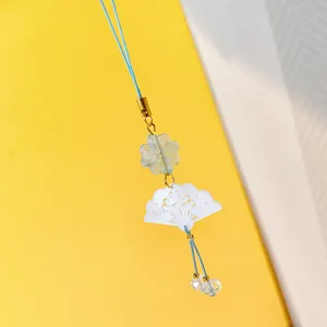 Gros plan detail du pendentif grigri telephone eventail coquillage acrylique ancien.