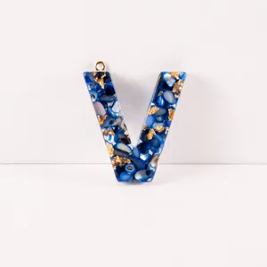 Resin letter V pendant DIY jewelry accessory with blue shell flakes and gold foil details.