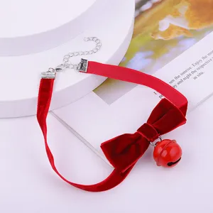 Gros plan détaillé du collier ras du cou en velours rouge avec un joli nœud et une cloche.