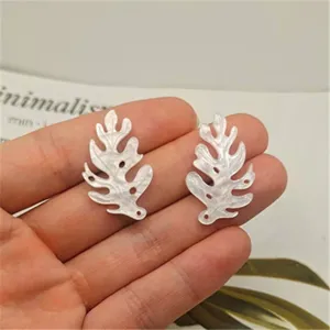 Detailed view of white acrylic leaf seashell charms, perfect for DIY hair accessories and crafts.