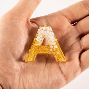Resin epoxy letter A DIY decorative accessory keychain pendant with gold glitter and white stones.