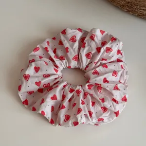 Primer plano detallado de un coletero rosa para el pelo con bonito estampado de corazones.