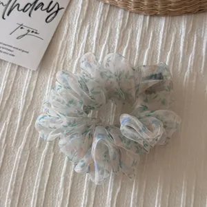 Floral organza scrunchie detail view, soft sheer hair tie with elegant floral pattern, chic accessory.