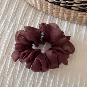 Close-up detail of a dark brown organza hair scrunchie, showing delicate sheer fabric and elastic design.