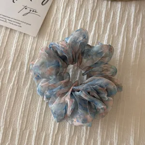 Detailed close-up of a dreamy blue and pink floral organza hair scrunchie, soft texture.
