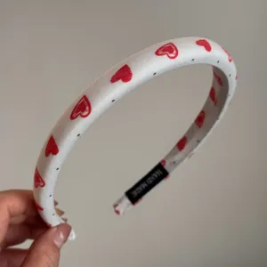Diadema de tela blanca con bonito estampado de corazones rojos y puntos grises, accesorio.