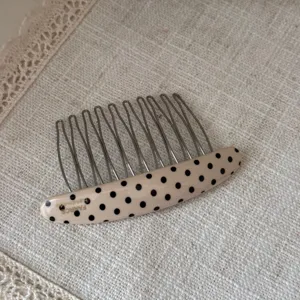 Close-up of elegant acetate hair comb with black polka dots and metal tines for chic styling.