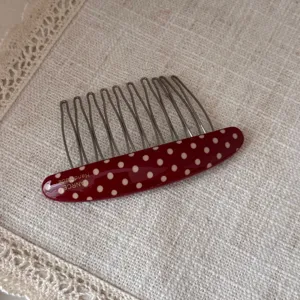 Red polka dot acetate hair comb detail shot, elegant metal teeth insert clip for daily hairstyling.