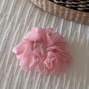 Detailed close-up of a pink organza hair scrunchie showing the fluffy translucent fabric texture.