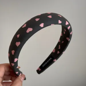 Primer plano detallado de una diadema acolchada de tela con un bonito patrón de corazones rosas.