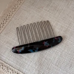 Detailed view of exquisite oval acetate hair insert comb with metal teeth for elegant styling.
