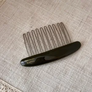 Close up view of elegant acetate hair insert comb, showing fine teeth and smooth glossy finish.