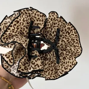 Dettaglio della molletta per capelli in tessuto leopardato, design con volant elegante per donne.