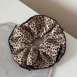 Vista dettagliata dell'elastico per capelli con stampa leopardata e bordo nero chic.