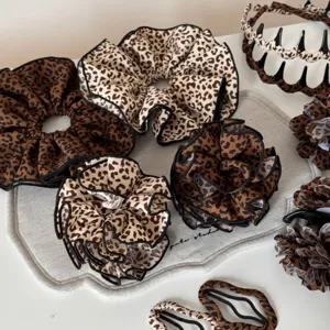 Vista dettagliata di elastici e mollette per capelli alla moda con stampa leopardata e bordo nero.