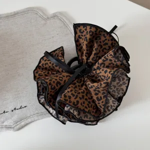 Vista dettagliata di molletta per capelli leopardata vintage con fiocco nero elegante.