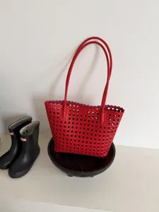 Vue détaillée du sac cabas en cuir tressé rouge, design souple ajouré, sac d'été élégant.