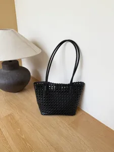 Vue détaillée du sac cabas en cuir tressé noir montrant sa texture douce et son savoir-faire.