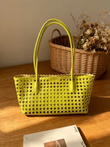 Detailed view of a stylish yellow woven leather shoulder tote bag with elegant braided handles.