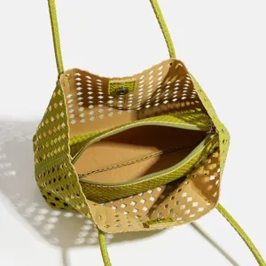 Green woven cutout shoulder tote bag detail showing interior zipper pouch and structure.