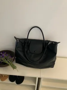 Detailansicht der schwarzen Pendlertasche mit Struktur, Henkel und faltbarem Überschlag.