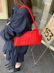 Detailed view of red woven leather shoulder bag, chic intrecciato texture and stylish strap.