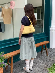 Detailed view of yellow woven shoulder bag worn by model outdoors, stylish fashion accessory.