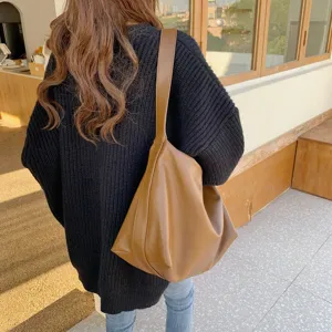 Vista dettagliata di una elegante borsa a tracolla marrone indossata da una modella.