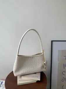 Detail shot of a chic cream woven shoulder bag on books, highlighting fine intrecciato texture.