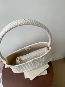 Detail shot of white woven handbag showcasing intricate leather intrecciato texture and design.