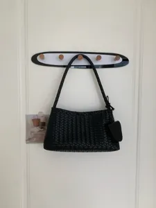 Black woven shoulder bag detail, elegant underarm baguette fashion handbag for women.